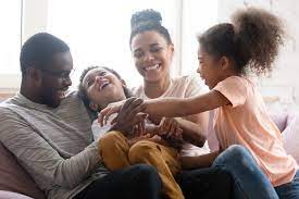 lachende familie mit kleinen Kindern beim spielen auf der Couch